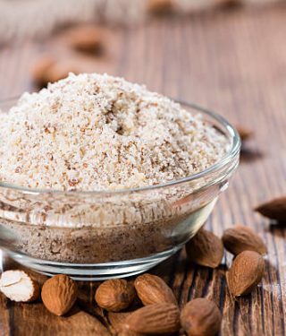 Heap of grated Almonds (close-up shot) on wooden background